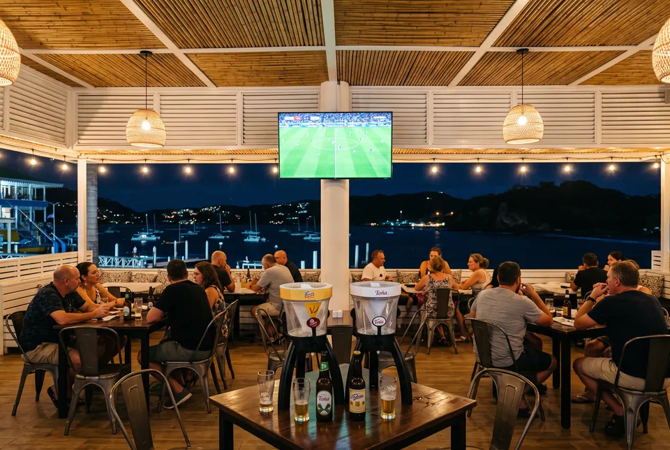 La terraza de noche con el partido en pantalla