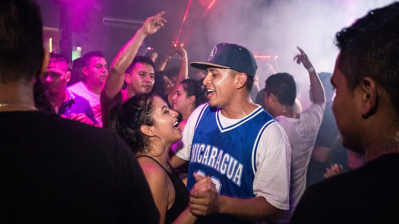 A couple dancing on a packed floor, in haze and purple light